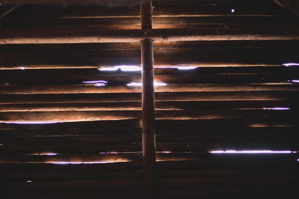 Free Image of Light peering through wooden planks at night 