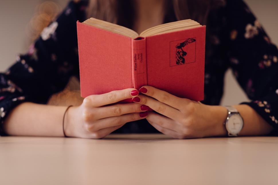 Free Image of Woman holding a book with red cover 