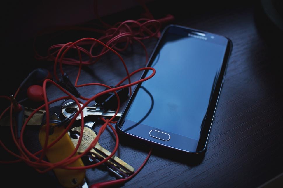 Free Image of Tangled earphones with smartphone on desk 