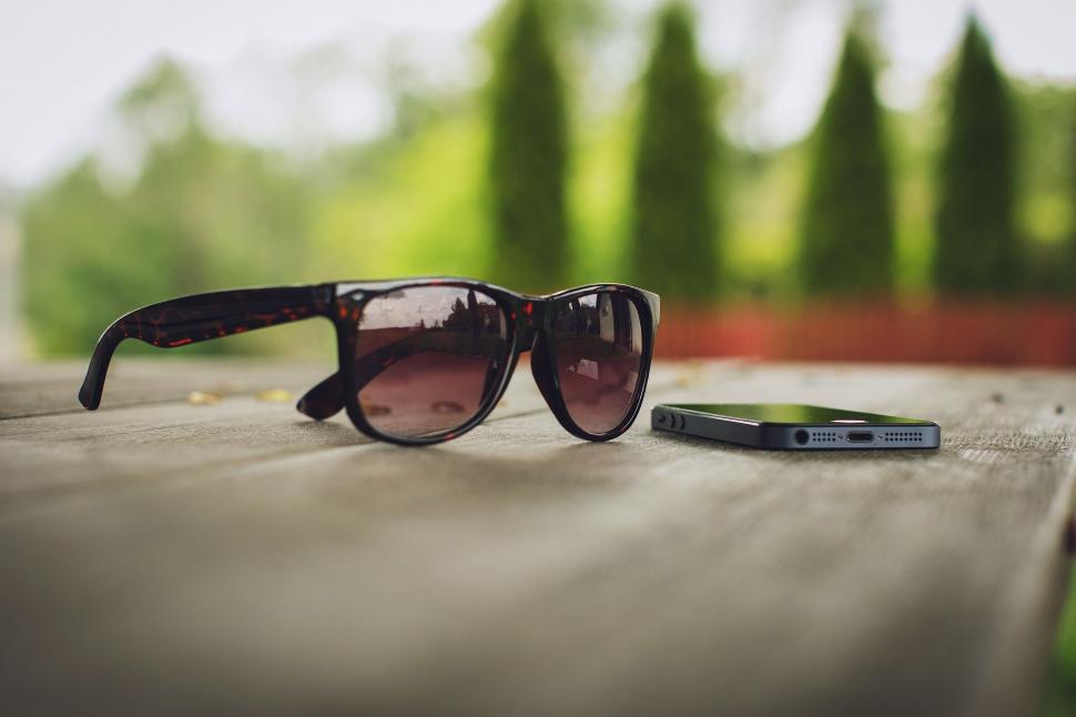 Free Image of Sunglasses and smartphone on a wooden surface 