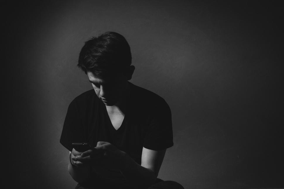 Free Image of Man on phone in dimly lit room with obscured face 