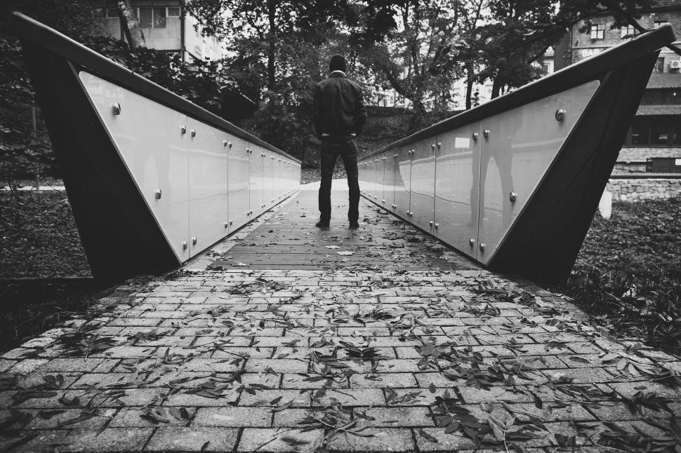 Free Image of Man walking on modern bridge in black and white 