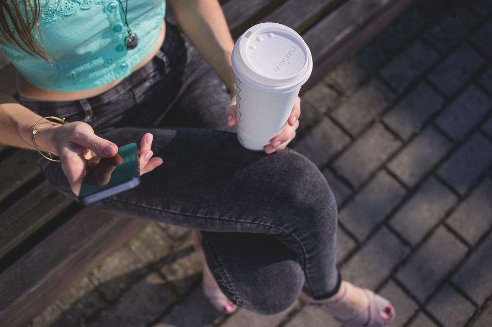 Free Image of Woman holding coffee and smartphone in city 