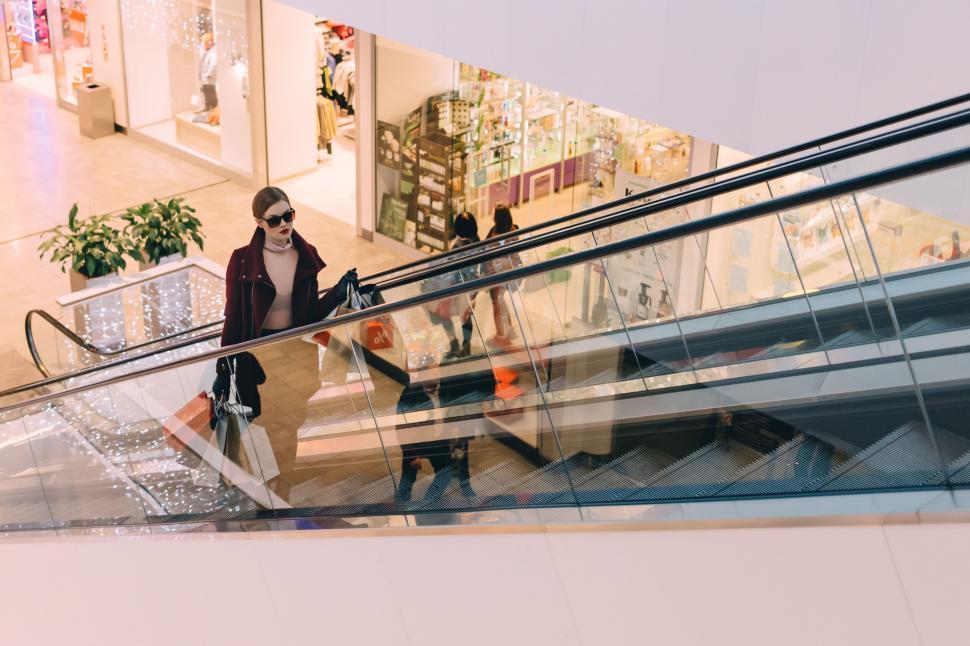 Free Image of Woman ascending an escalator in a mall 