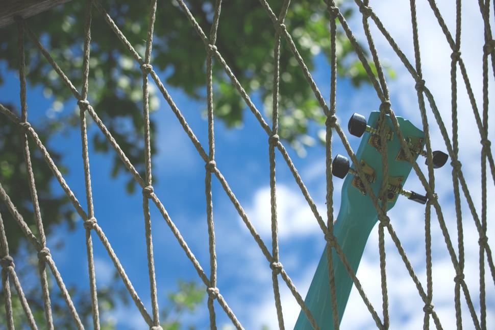 Free Image of Skateboard hanging on netted fence against sky 