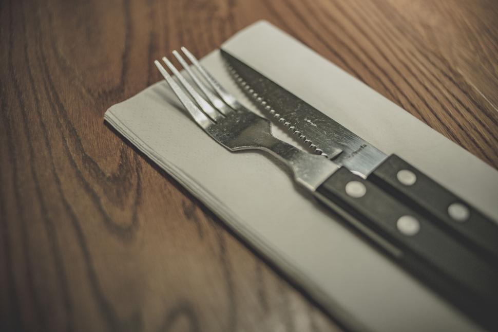 Free Image of Fork and knife on a napkin on wooden table 