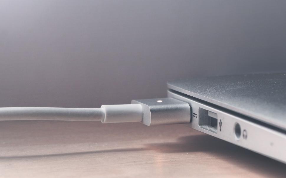 Free Image of Laptop charger connected to laptop on desk 