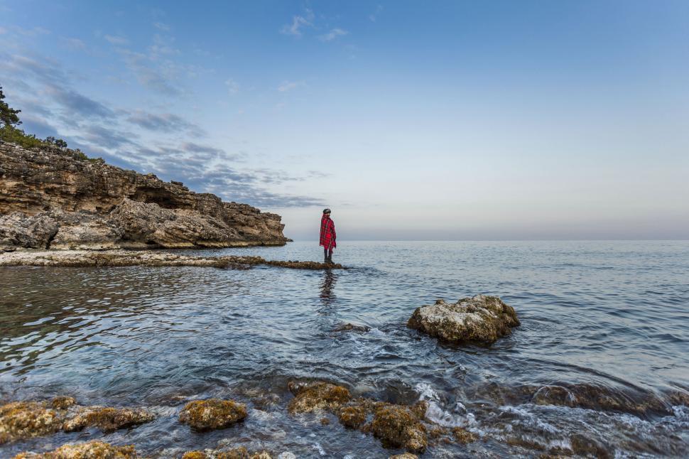 Free Image of Man walking on a rocky seashore at dawn 