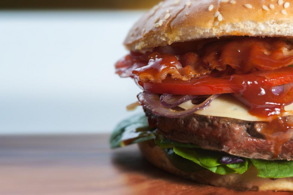 Free Image of Juicy cheeseburger with fresh toppings close-up 