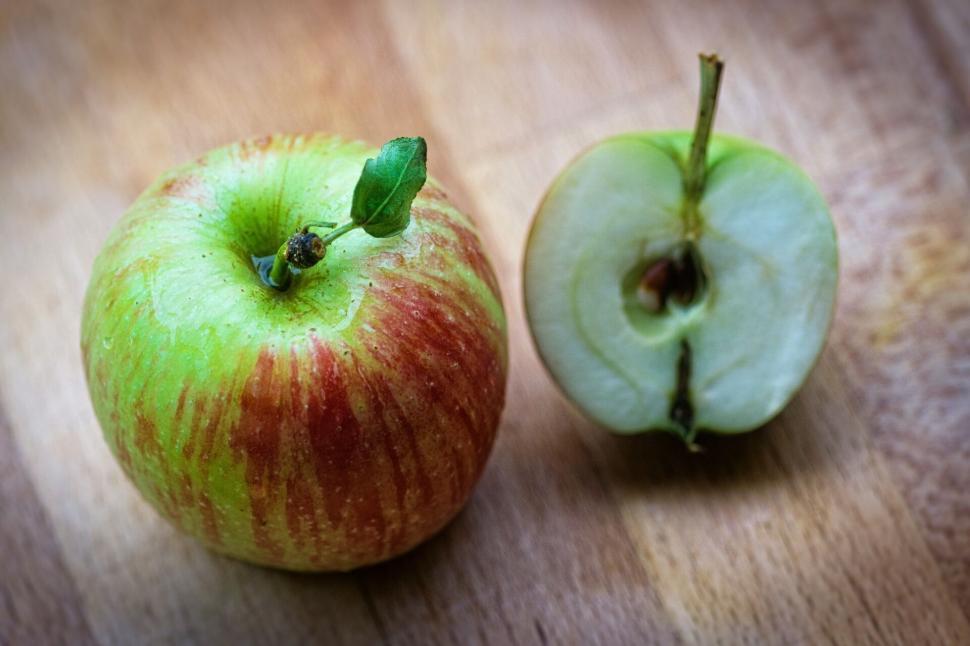Free Image of Fresh apple cut in half on wooden surface 