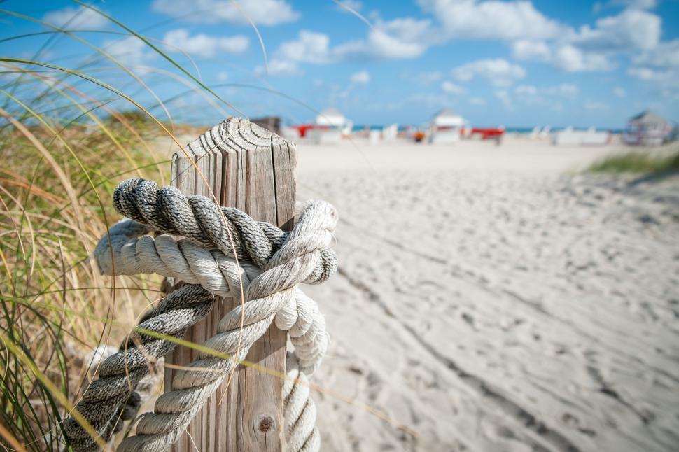 Free Image of Rope tied to a wooden post on sandy beach 