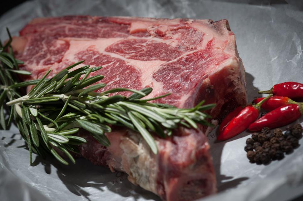 Free Image of Raw steak with herbs on paper background 