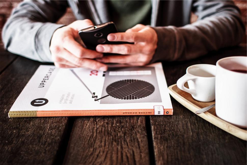 Free Image of Person using smartphone at cafe table 