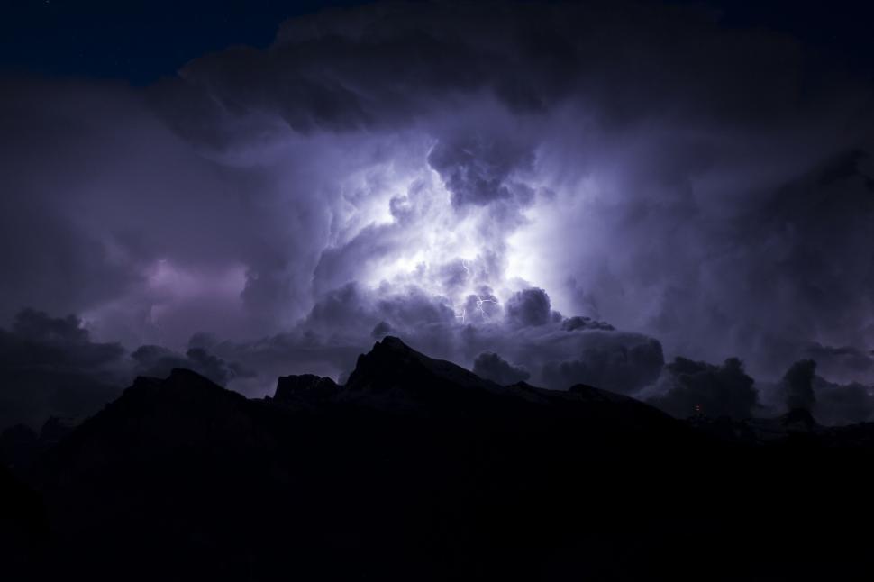 Free Image of Thunderstorm lighting up the night sky over peaks 