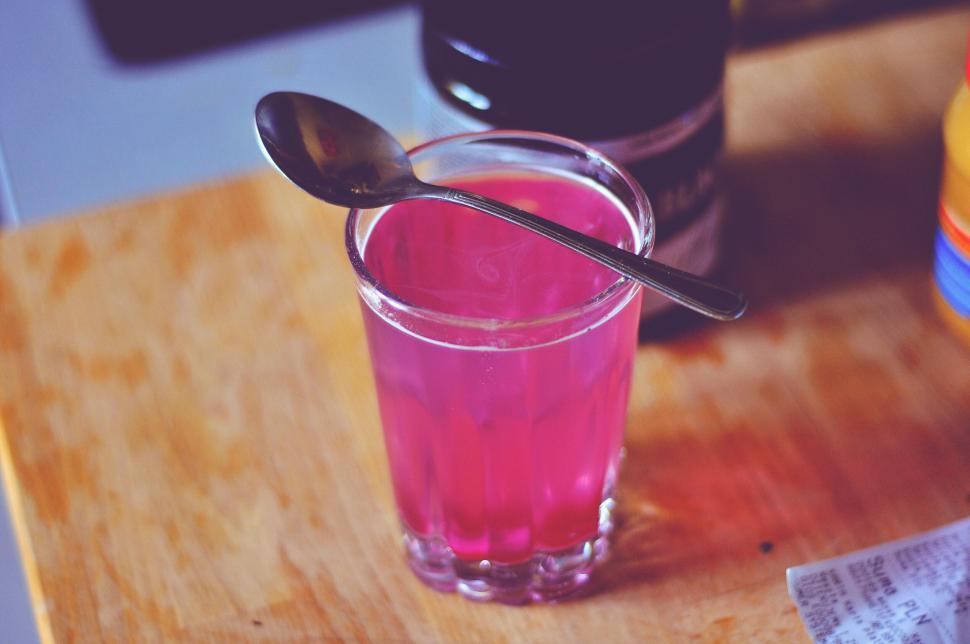 Free Image of Glass of pink liquid with a spoon on a table 