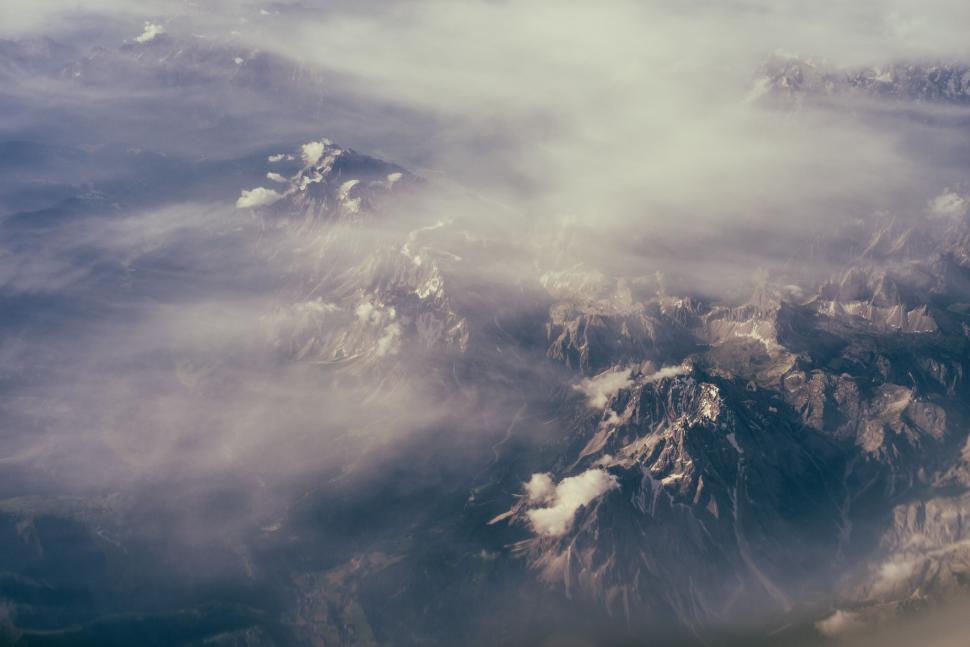 Free Image of Aerial view of mountain peaks poking through clouds 
