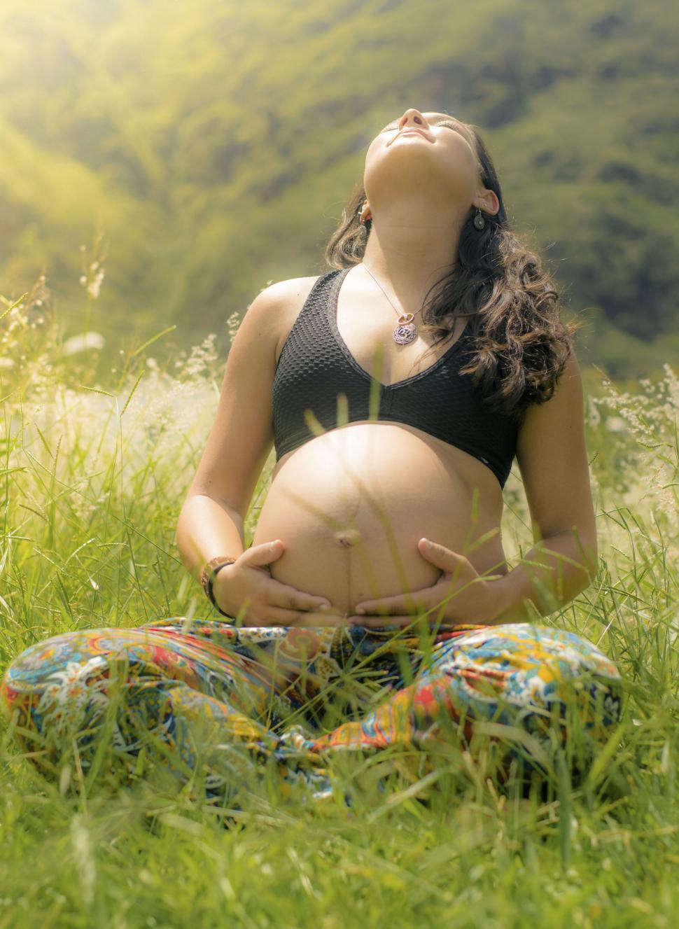 Free Image of Pregnant woman meditating in grassy field 
