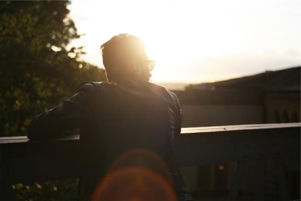 Free Image of Silhouetted man looking at the sunset from bridge 