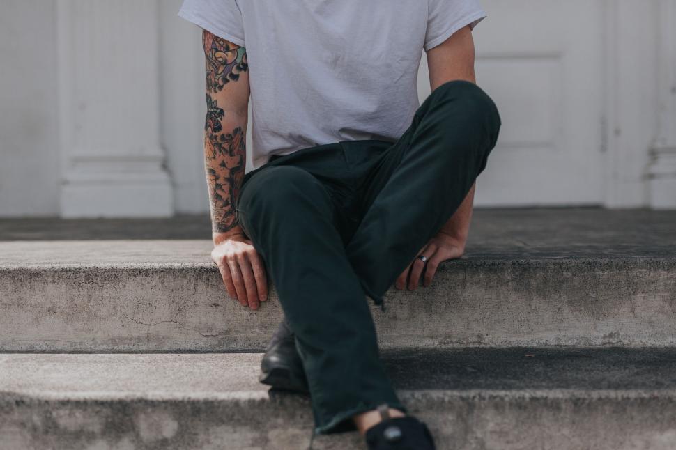 Free Image of Tattooed man sitting on steps 