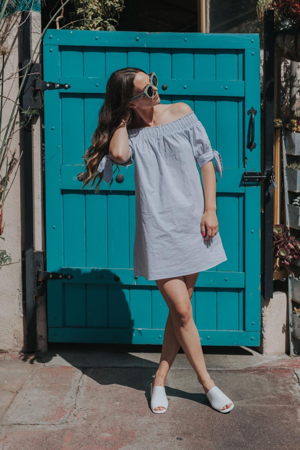 Free Image of Woman in blue dress standing by teal door 