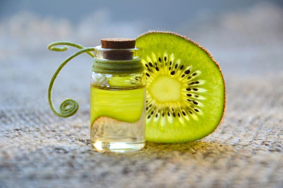 Free Image of Kiwi essential oil in a small bottle with kiwi slice 