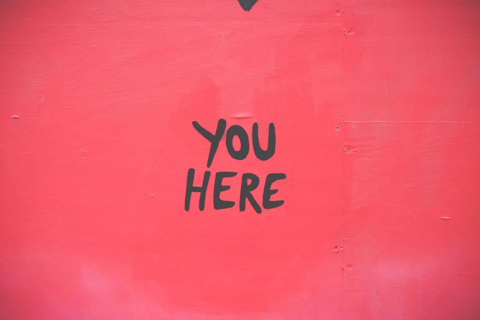 Free Image of Bold YOU HERE sign on a vibrant red wall 