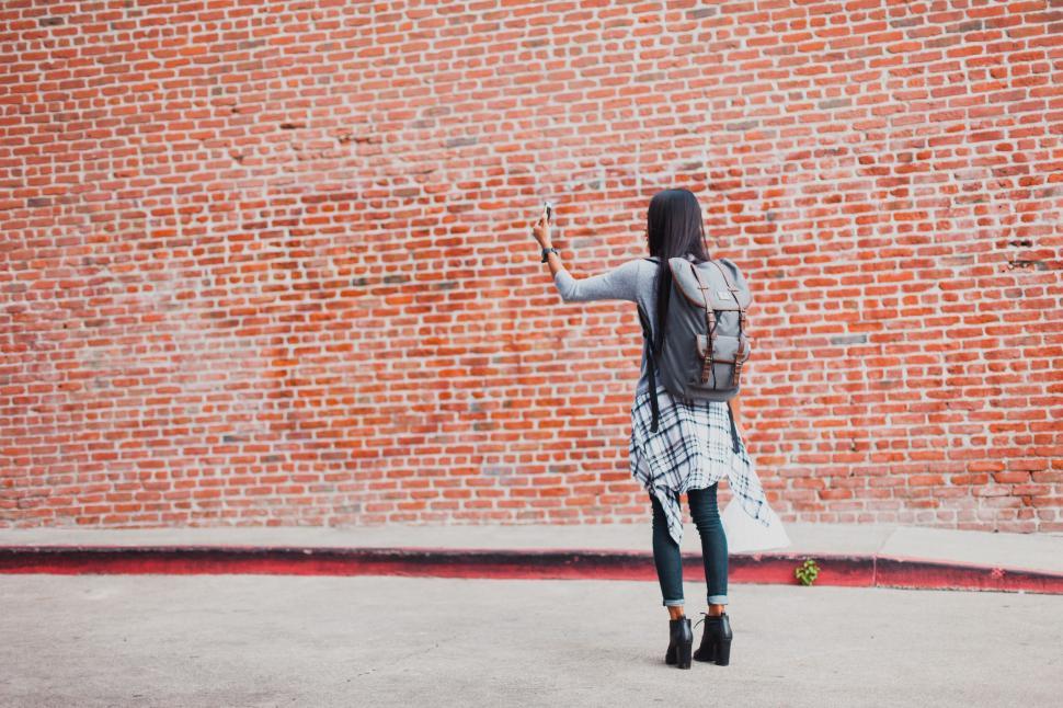 Free Image of Woman taking a selfie against a brick wall 