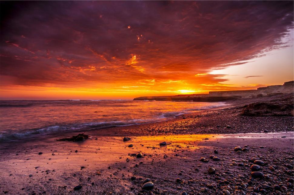 Free Image of Vibrant ocean sunset on rocky beach 