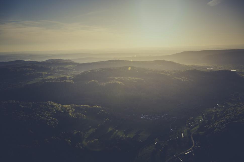 Free Image of Misty sunrise over lush green rolling hills 
