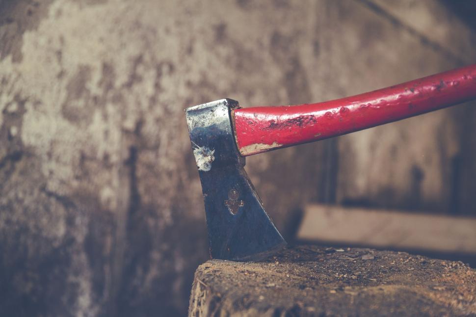 Free Image of Red-handled axe embedded in wooden stump 
