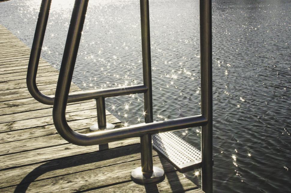 Free Image of Lakeside railing with sparkling water 