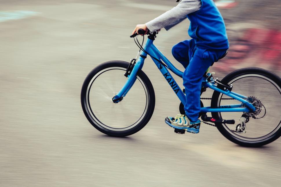 Free Image of Child riding a blue bicycle in motion 