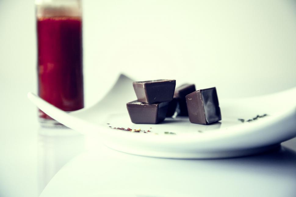 Free Image of Dark chocolates on a plate with a juice glass 