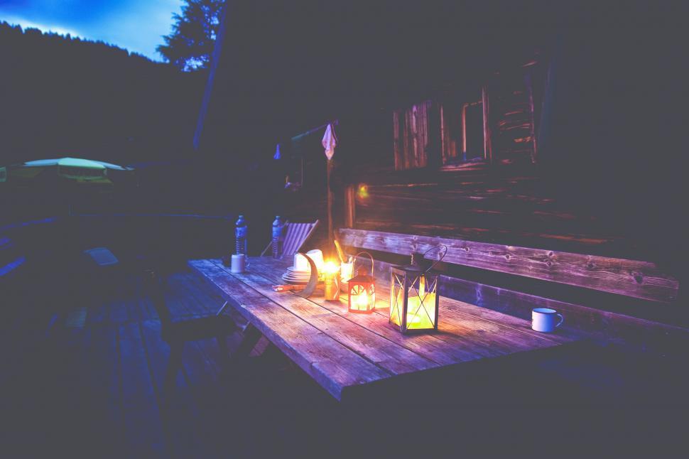 Free Image of Lit lanterns on rustic outdoor wooden table 