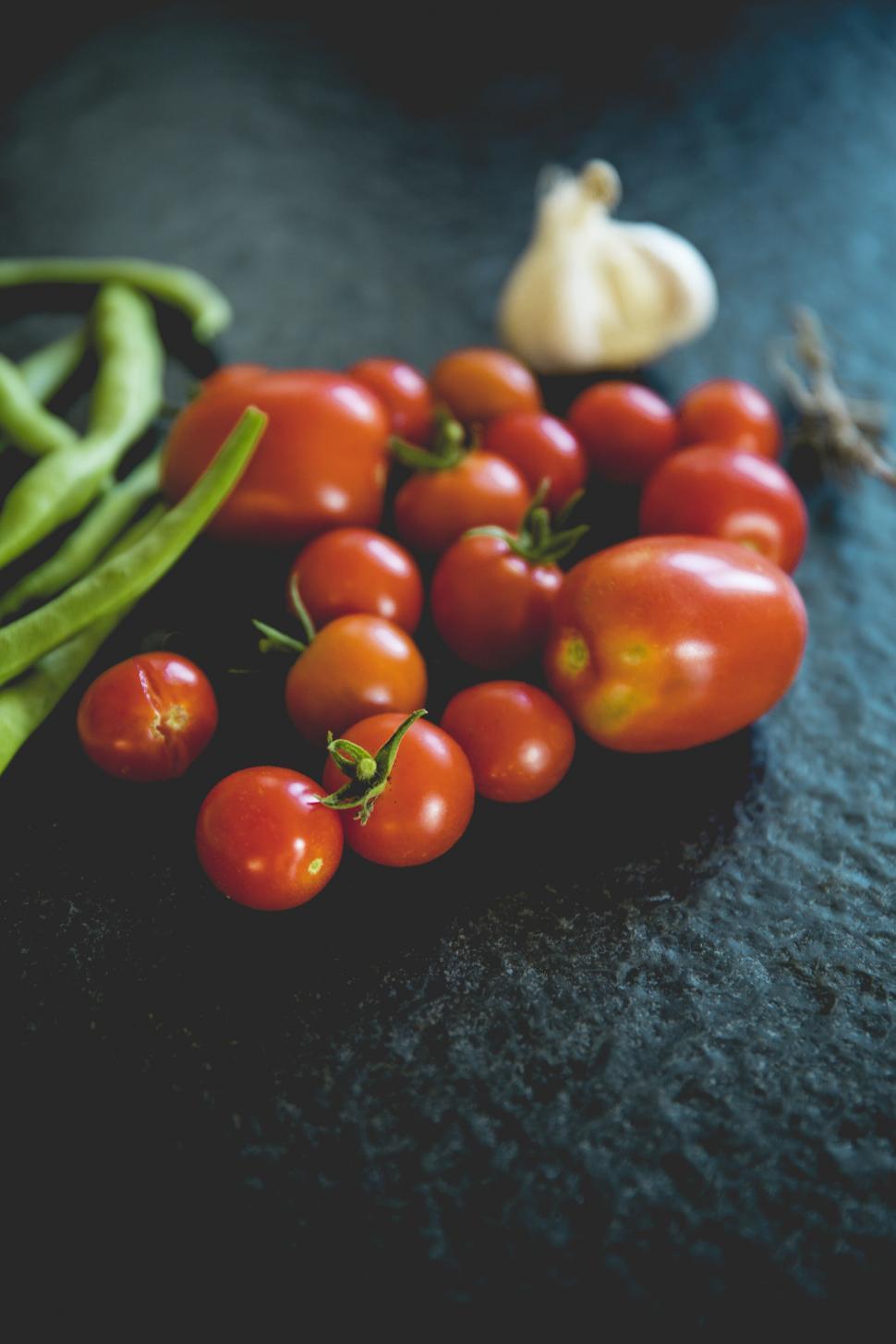 Free Image of Fresh tomatoes with garlic and beans on dark surface 