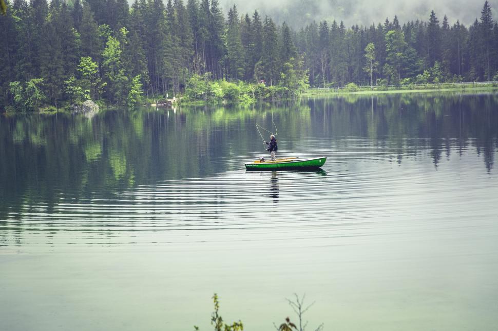 Free Image of Fisherman in a boat on a calm lake 