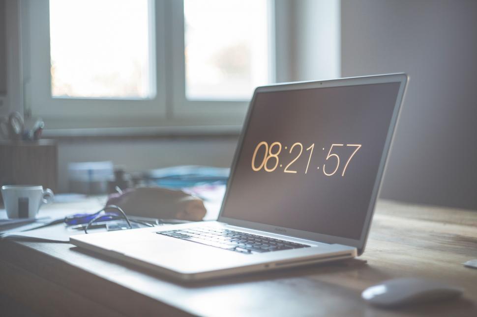 Free Image of Laptop displaying time on wooden desk 