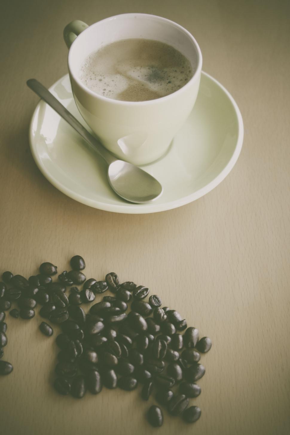 Free Image of A cup of coffee with scattered beans 