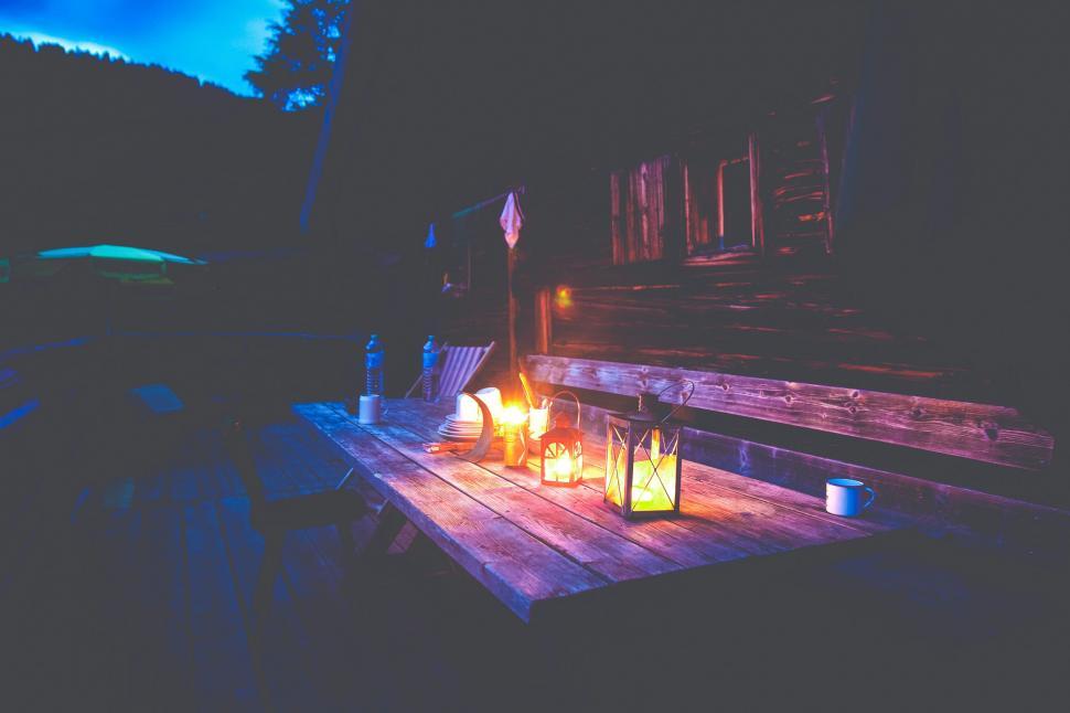 Free Image of Warm lanterns illuminate a rustic outdoor table 
