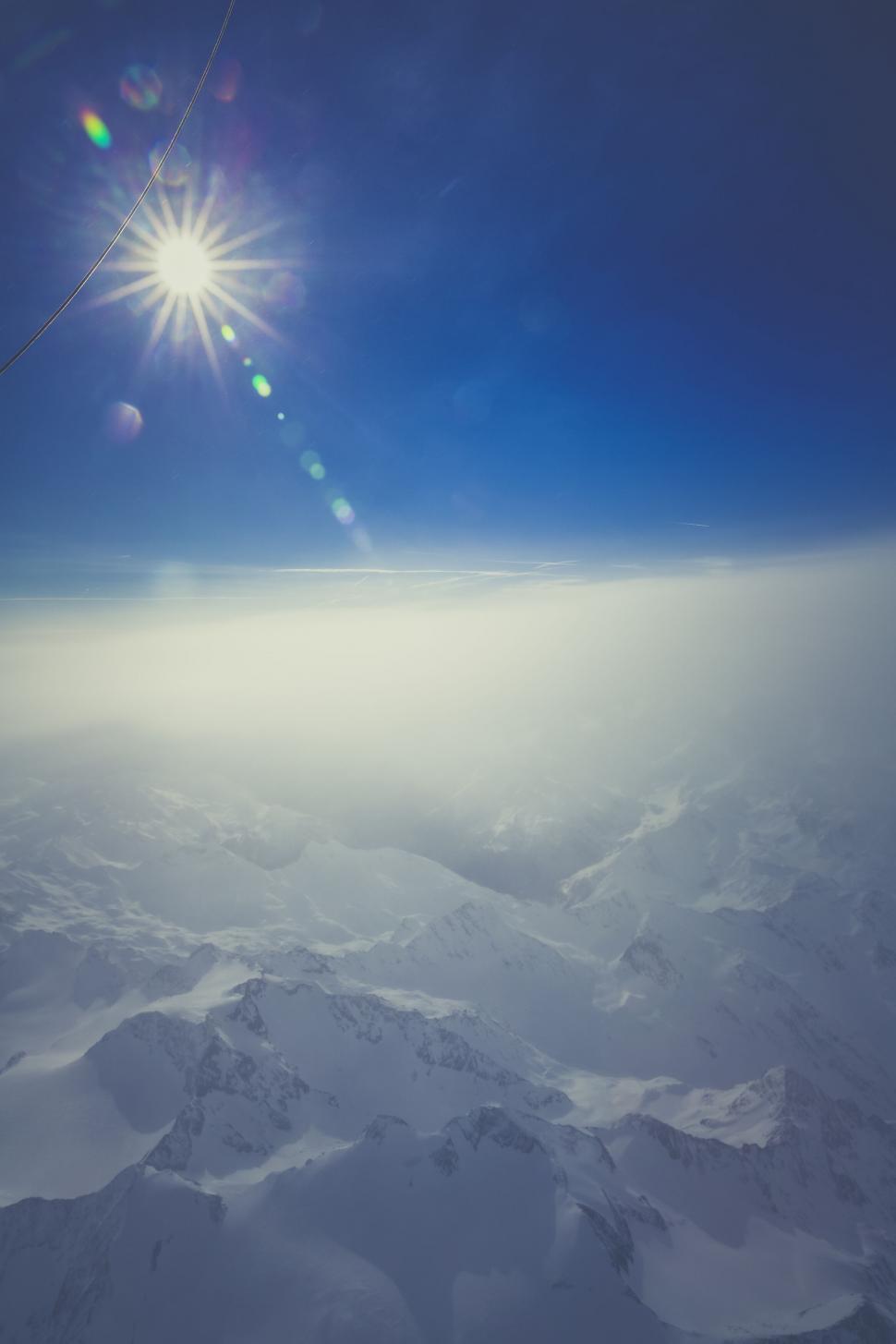 Free Image of Radiant sun flare over snowy mountain peaks 