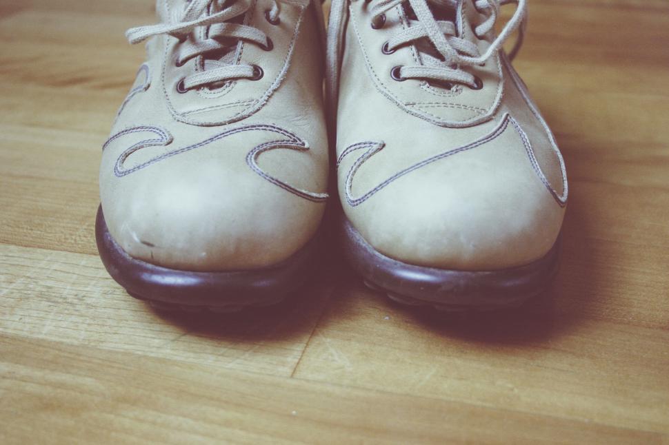 Free Image of Pair of worn sneakers on wooden floor 