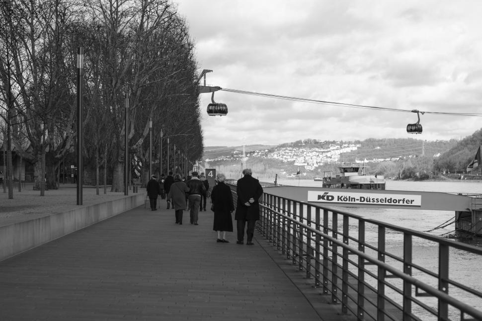 Free Image of Riverside walkway with people and cable cars 