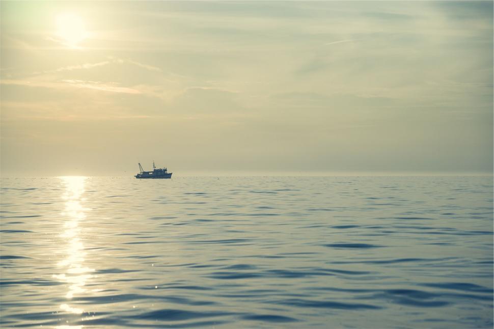 Free Image of Solitary boat on a calm ocean at sunset 