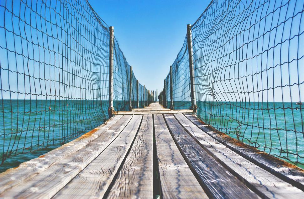 Free Image of Wooden dock with net leading into turquoise sea 