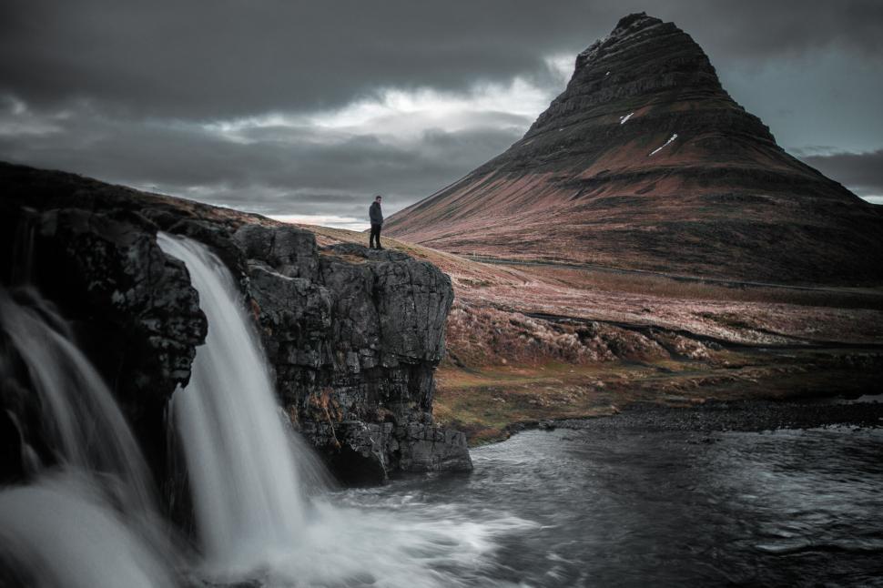 Free Image of Solitary figure by a majestic mountain waterfall 