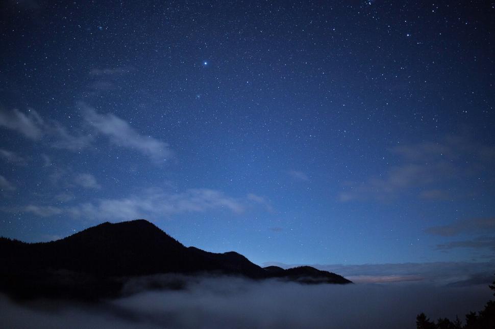 Free Image of Starry night sky over a calm mountain landscape 