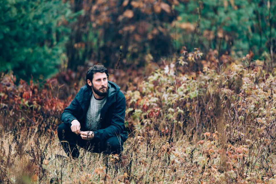 Free Image of Man crouched in autumnal field 