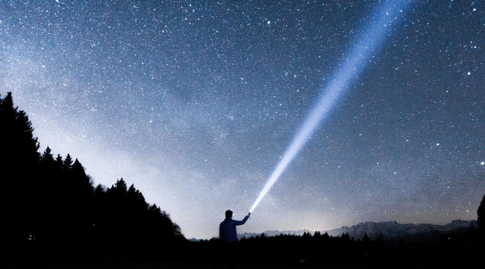 Free Image of Man pointing flashlight towards starry sky 