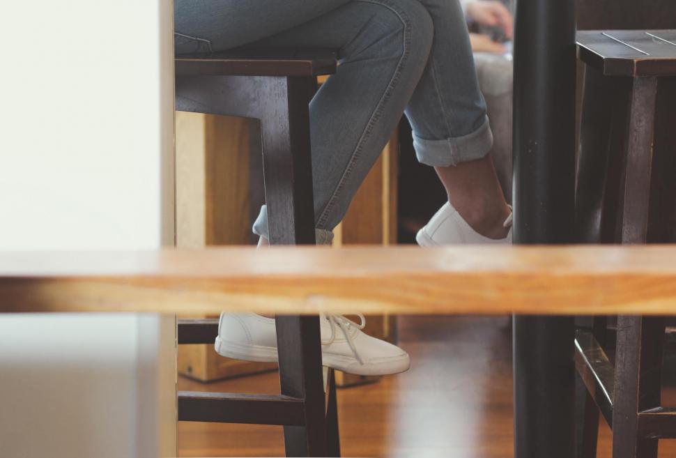 Free Image of Person sitting in a cafe with white sneakers 