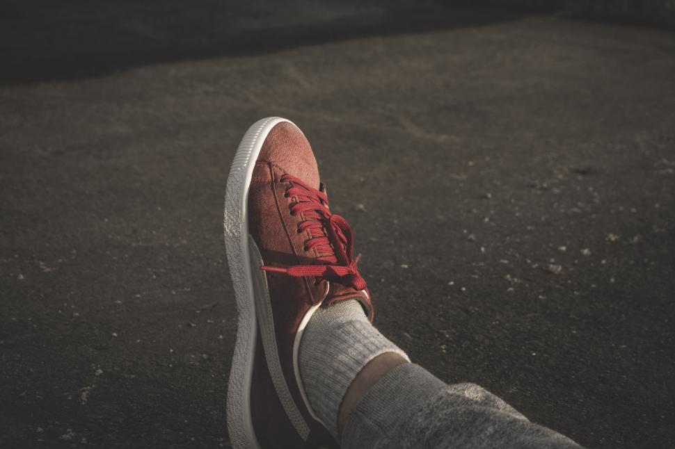 Free Image of Close-up of red sneaker on asphalt 